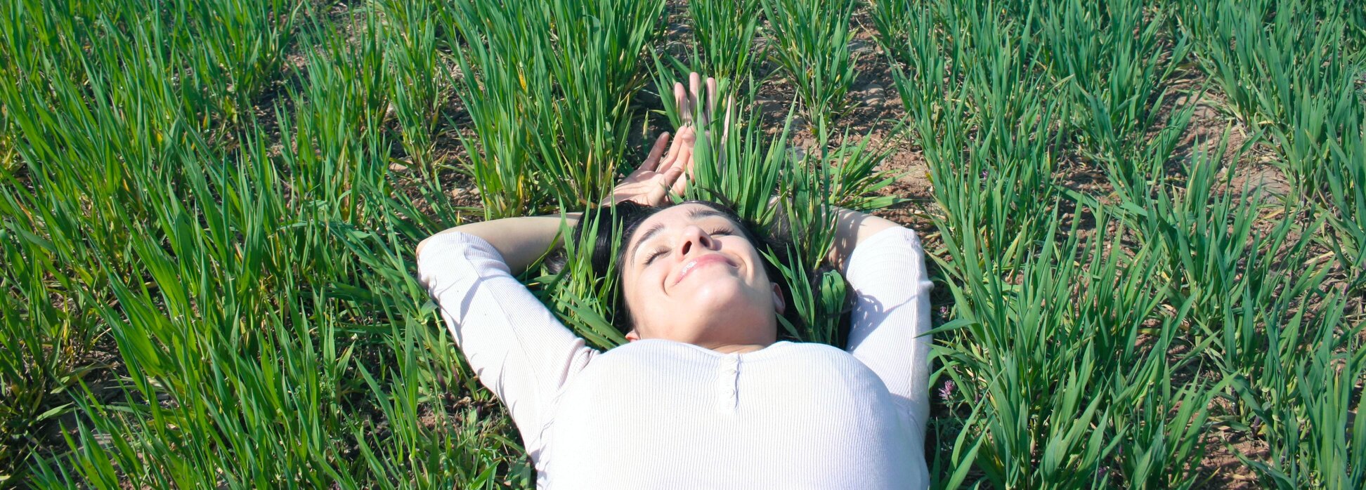 Jeune femme relaxée allongée dans l'herbe, yeux clos