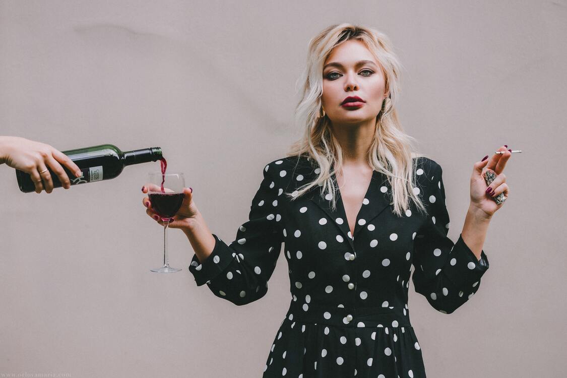 Jeune femme maquillée avec cigarette et verre de vin